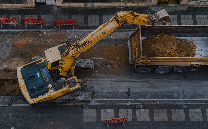 Excavator Dumping Dirt Into Dumpster